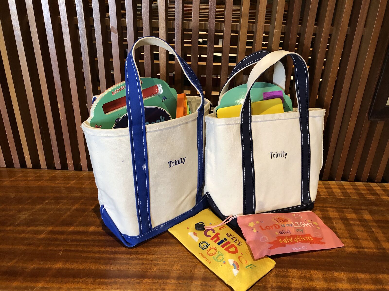 Two Trinity canvas tote bags filled with coloring books and activities for children